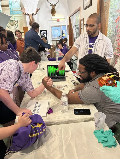 Marquise showing students a live muscle-activity recording at Kids' Day at the Museum